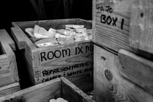 A series of wooden boxes. Clay and stone pieces fill the wooden boxes. This image is in black and white.