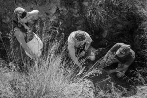 Students listening to their professor as they examine the archaeological site. This image is in black and white.