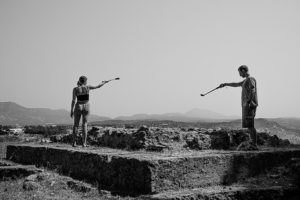 Two students working with cameras to get a scope over the ruins of a roman building. This image is in black and white.