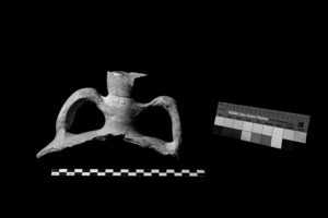 On the left, the handles and mouth of an amphora. On the right, a Kodak color control patch sheet. The image is in black and white.