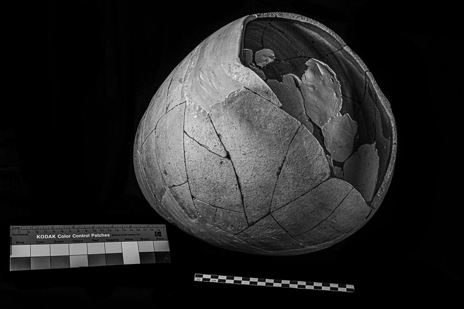 An amphora, staged with a view of the opening showing the patched interior holding the pieces of the artifact together. A Kodak color patch sheet sits on the left of the image.